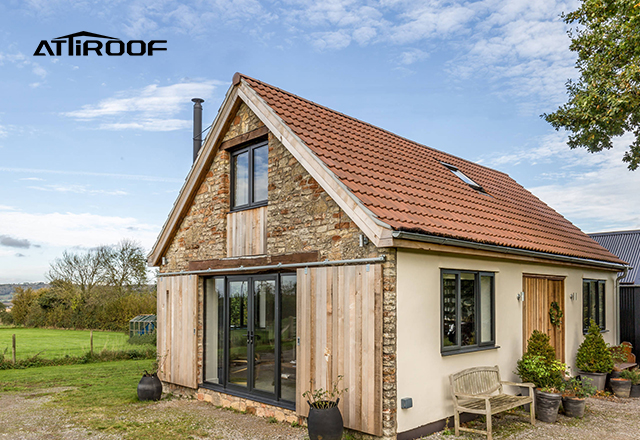 Modern cottage with stone-coated metal roof tiles, maintaining a pristine and well-preserved appearance against a rustic backdrop, exemplifying long-term aesthetic durability.