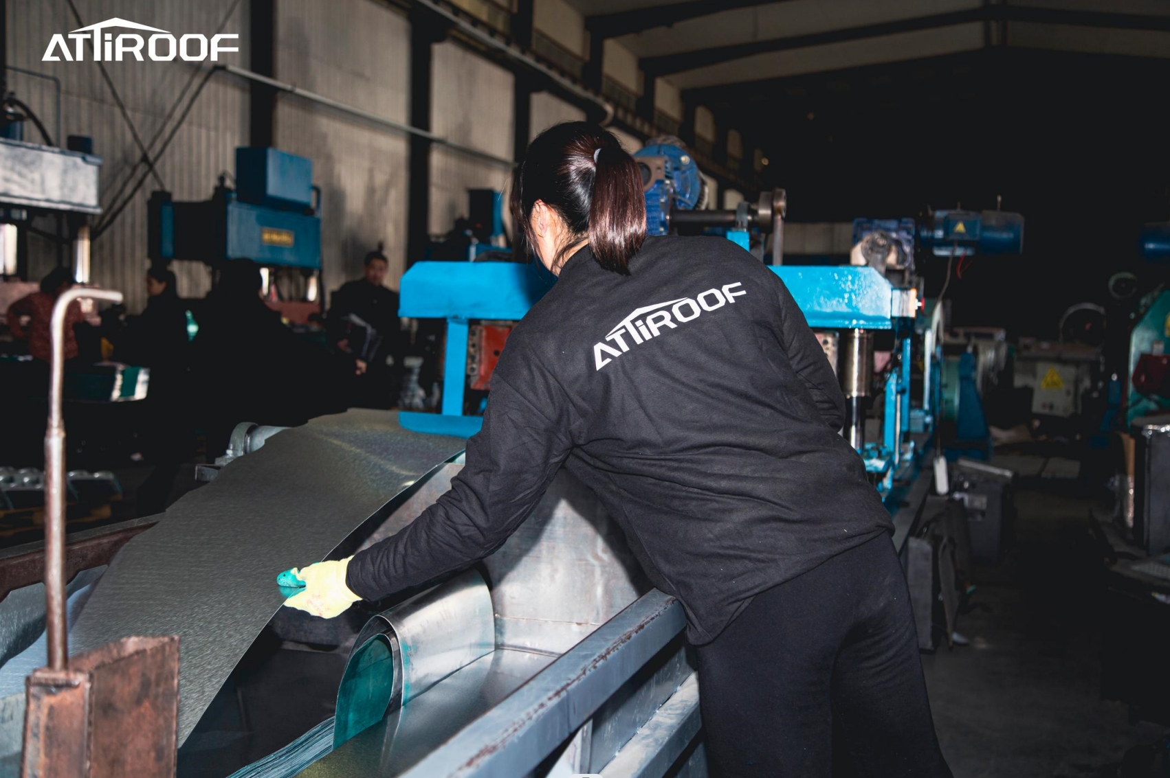 An Attiroof employee operating high-efficiency machinery in a manufacturing plant, demonstrating optimized material use and waste reduction.