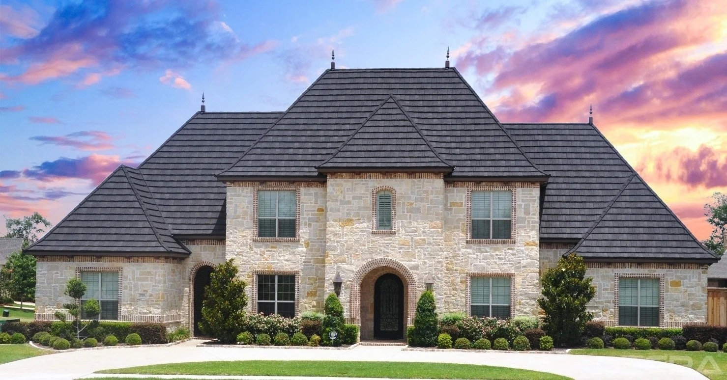 Elegant stone-coated metal roof tiles on a residential house, showcasing durability and aesthetic appeal against a sunset sky.