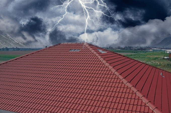 Red tile roof enduring a thunderstorm, showcasing durability and weather resistance in extreme conditions.