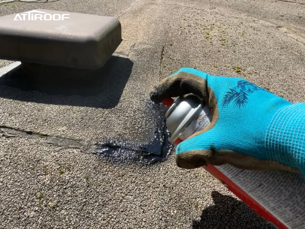 Close-up of roof repair in progress, demonstrating the application of a sealing spray to fix a damaged area on a shingle roof.